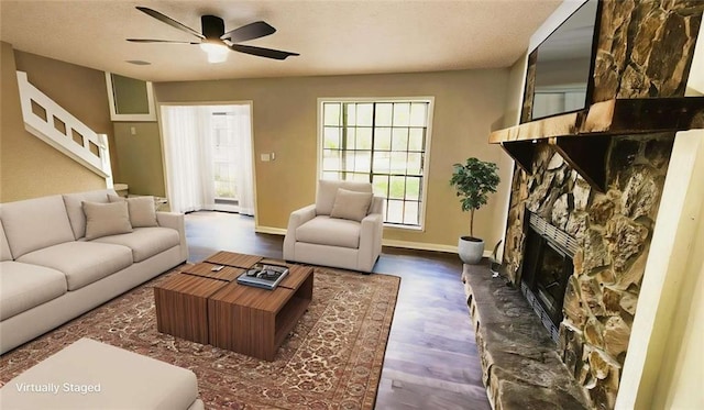 living area featuring stairs, wood finished floors, a fireplace, baseboards, and a ceiling fan