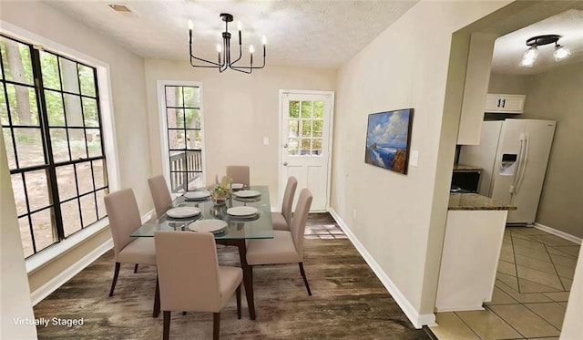 dining area with baseboards, visible vents, a textured ceiling, and a chandelier