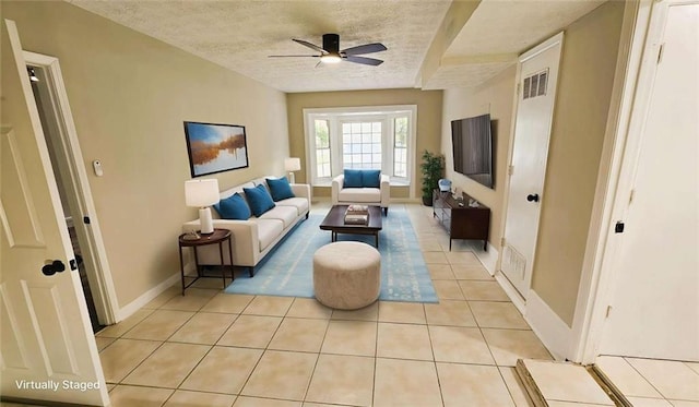 living area featuring baseboards, a textured ceiling, ceiling fan, and light tile patterned flooring