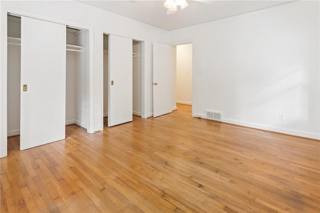 unfurnished bedroom featuring ceiling fan, two closets, and light hardwood / wood-style floors