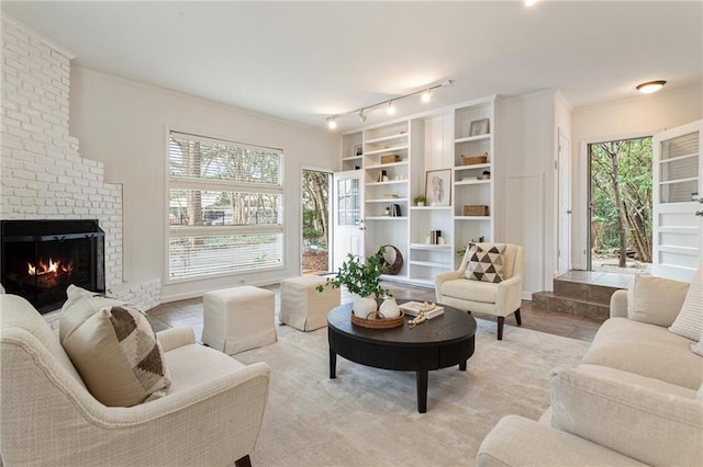 tiled living room with a brick fireplace, crown molding, track lighting, and a healthy amount of sunlight