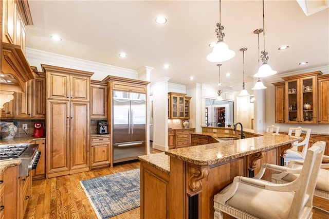 5352 Lacosta Ln, Alpharetta, GA 30022 - kitchen featuring stainless steel appliances, a sink, brown cabinets, ornamental molding, and light wood-style floors