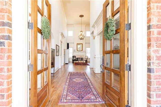 5352 Lacosta Ln, Alpharetta, GA 30022 - entrance foyer featuring light wood-style floors, a chandelier, a towering ceiling, ornate columns, and french doors