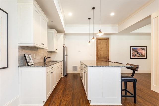 5352 Lacosta Ln, Alpharetta, GA 30022 - kitchen with freestanding refrigerator, a center island, crown molding, dark wood-type flooring, and a kitchen breakfast bar