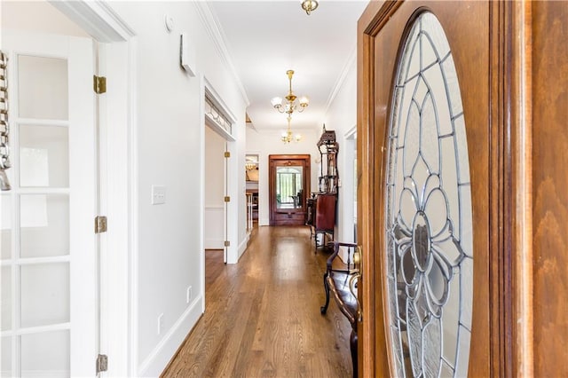 hallway with crown molding, baseboards, a notable chandelier, and wood finished floors