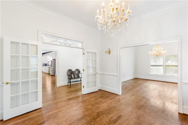 unfurnished dining area featuring a wealth of natural light, ornamental molding, wood finished floors, and a notable chandelier