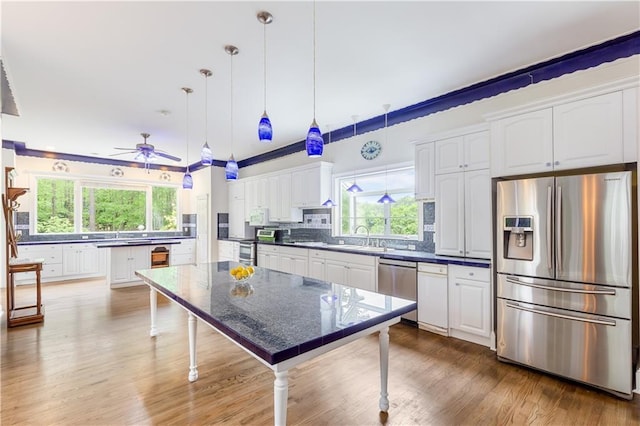 kitchen with white cabinets, appliances with stainless steel finishes, a sink, a ceiling fan, and tasteful backsplash