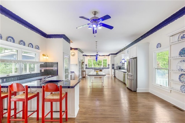 kitchen featuring a ceiling fan, visible vents, dark countertops, a sink, and freestanding refrigerator
