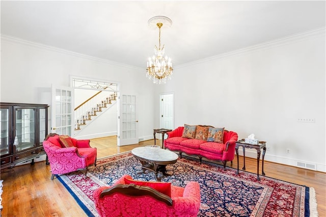living area with crown molding, baseboards, wood finished floors, and a chandelier