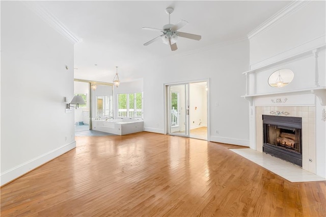 unfurnished living room with a ceiling fan, crown molding, a fireplace, light wood-type flooring, and baseboards