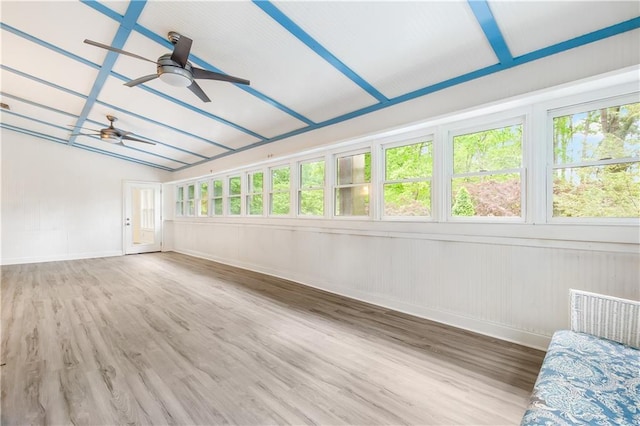 unfurnished sunroom featuring baseboards, a wooden deck, wood finished floors, and a wealth of natural light