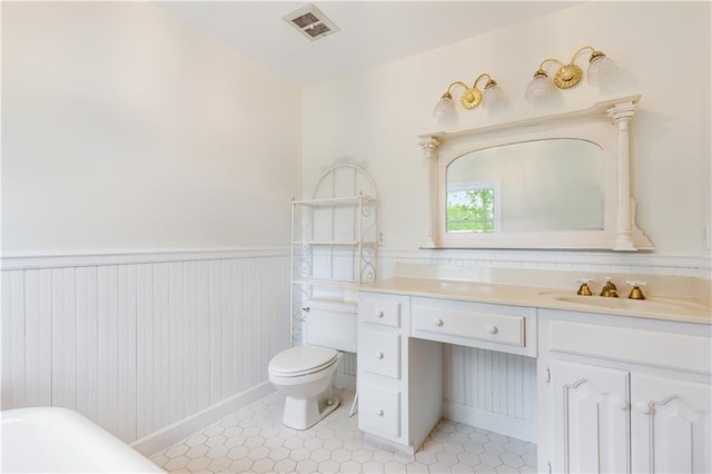 bathroom featuring visible vents, wainscoting, vanity, tile patterned floors, and toilet