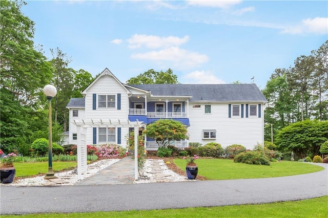 traditional home featuring a pergola, a balcony, and a front yard
