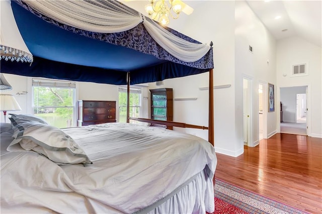 bedroom featuring baseboards, a chandelier, wood finished floors, and visible vents