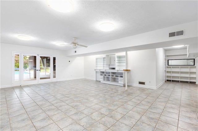 unfurnished living room featuring visible vents, a ceiling fan, a textured ceiling, and baseboards