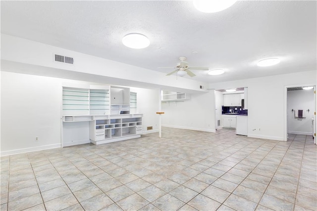 unfurnished living room with baseboards, ceiling fan, a textured ceiling, and visible vents