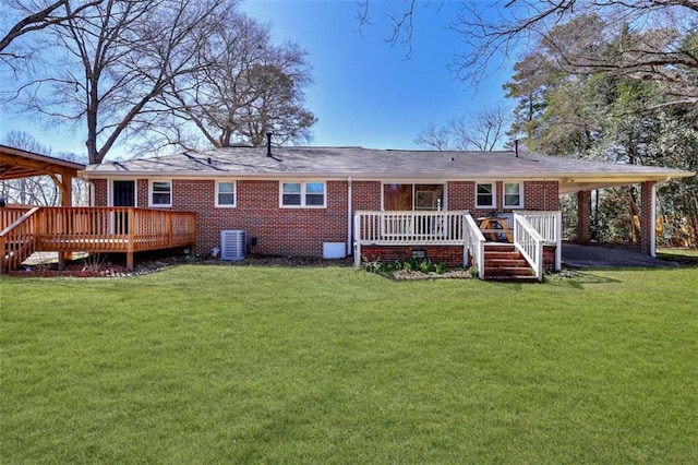 back of property with central air condition unit, a lawn, a deck, and brick siding