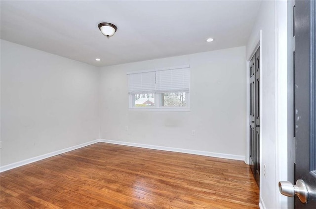 spare room with recessed lighting, baseboards, and wood finished floors