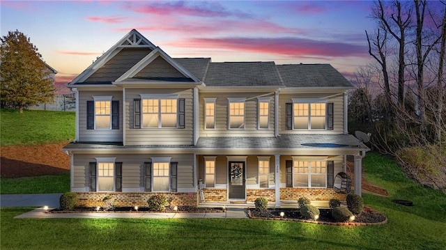 craftsman house with a porch, a front yard, and brick siding