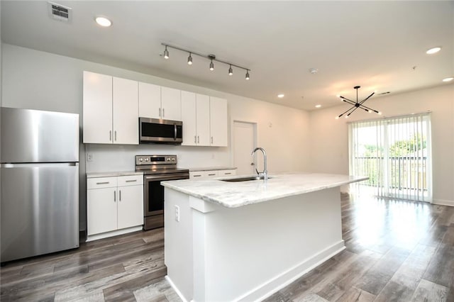 kitchen with white cabinets, stainless steel appliances, a center island with sink, and sink