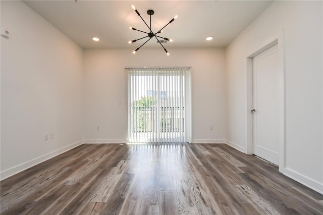 spare room featuring dark hardwood / wood-style flooring and a notable chandelier