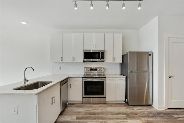 kitchen with light wood-type flooring, white cabinetry, sink, and appliances with stainless steel finishes