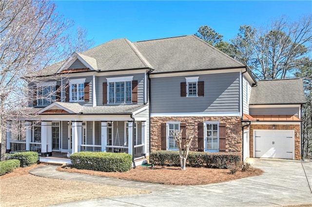 view of front of home with stone siding, a porch, concrete driveway, and a shingled roof