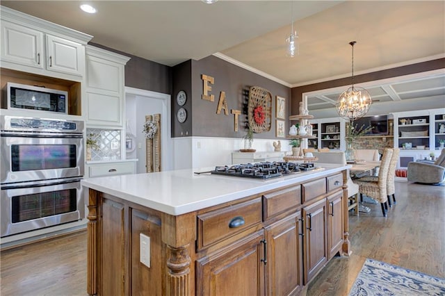 kitchen with stainless steel appliances, wood finished floors, white cabinetry, light countertops, and a center island