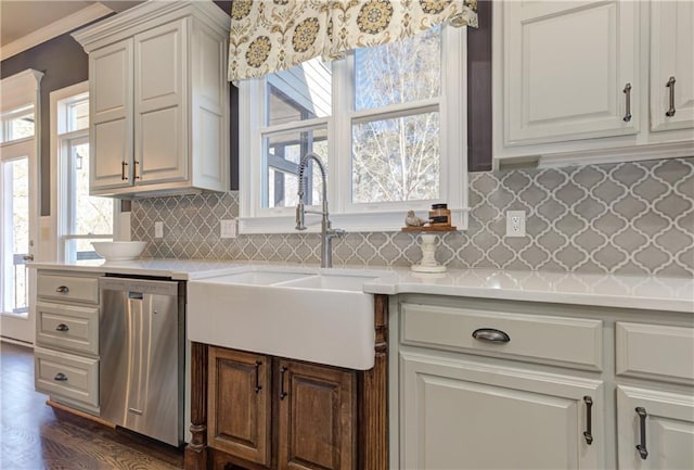 kitchen with decorative backsplash, dark wood-style floors, light countertops, stainless steel dishwasher, and a sink