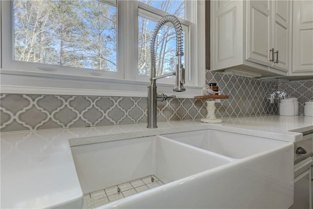 room details with white cabinets, light countertops, a sink, and decorative backsplash