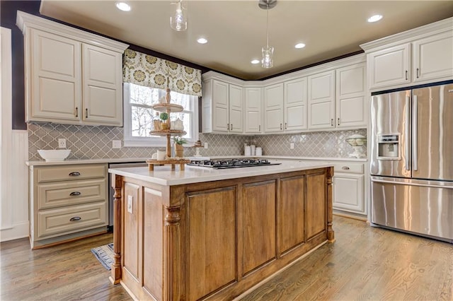 kitchen with stainless steel appliances, white cabinets, light countertops, a center island, and light wood finished floors