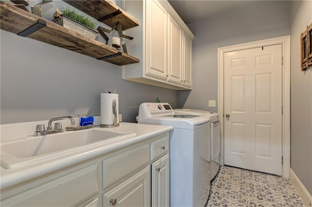 clothes washing area with baseboards, a sink, cabinet space, and washer and dryer