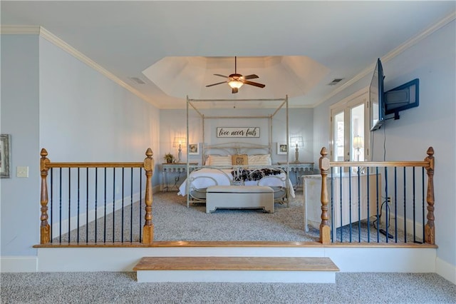 bedroom with carpet floors, crown molding, a raised ceiling, visible vents, and baseboards