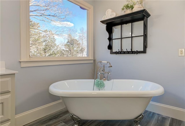 full bathroom featuring a freestanding bath, baseboards, and wood finished floors