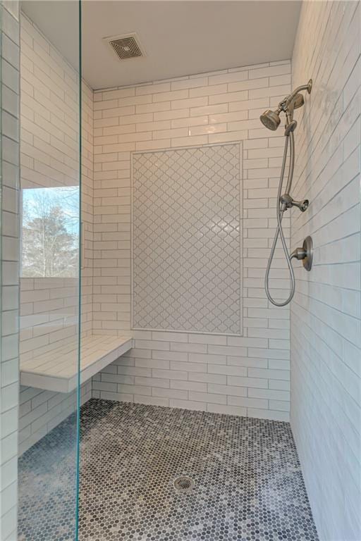 bathroom with visible vents and a tile shower