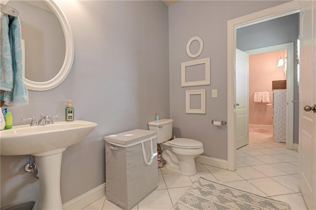 half bathroom featuring tile patterned flooring, baseboards, and toilet