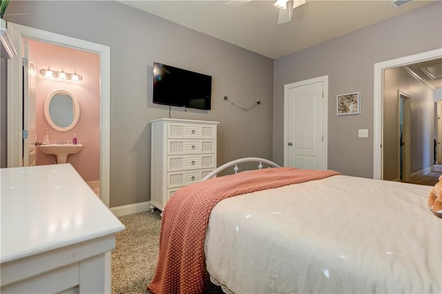 bedroom featuring light carpet, attic access, baseboards, ensuite bathroom, and a sink