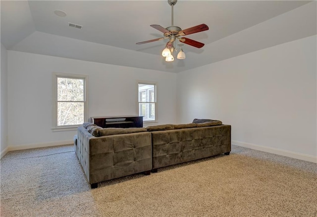 living room with light colored carpet, a tray ceiling, and a healthy amount of sunlight