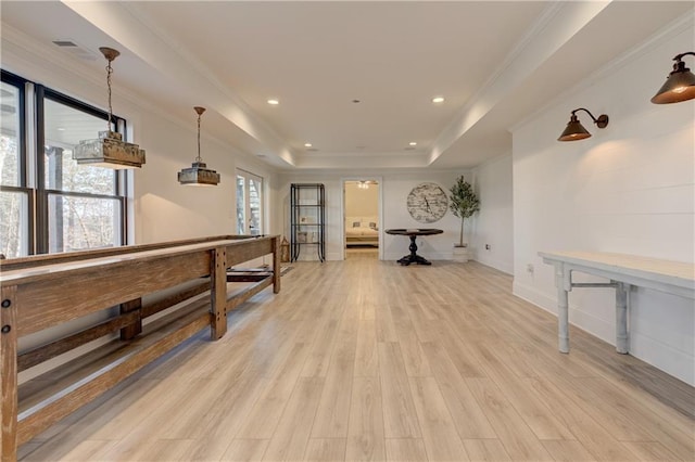 rec room with ornamental molding, light wood finished floors, a raised ceiling, and recessed lighting