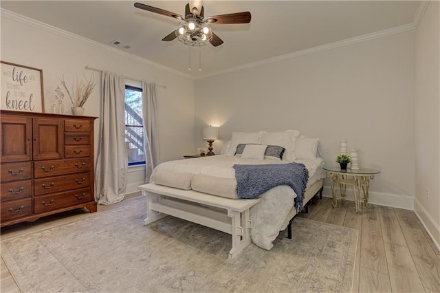 bedroom featuring baseboards, ornamental molding, visible vents, and light wood-style floors