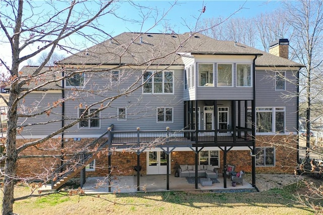 back of house featuring stone siding, stairway, a wooden deck, a chimney, and a patio area