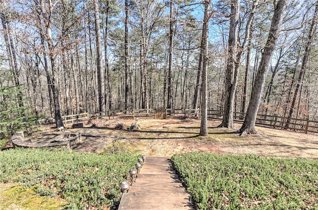 view of yard featuring a forest view and fence