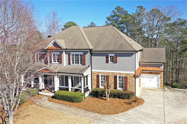 view of front of house featuring stone siding, roof with shingles, concrete driveway, and covered porch