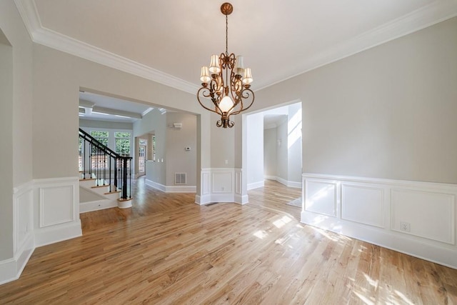 unfurnished dining area with light wood-style floors, stairway, crown molding, and an inviting chandelier