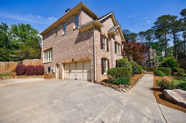 view of home's exterior featuring fence, driveway, brick siding, and a garage