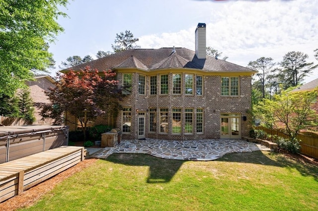back of house with a fenced backyard, a hot tub, a yard, a patio, and brick siding