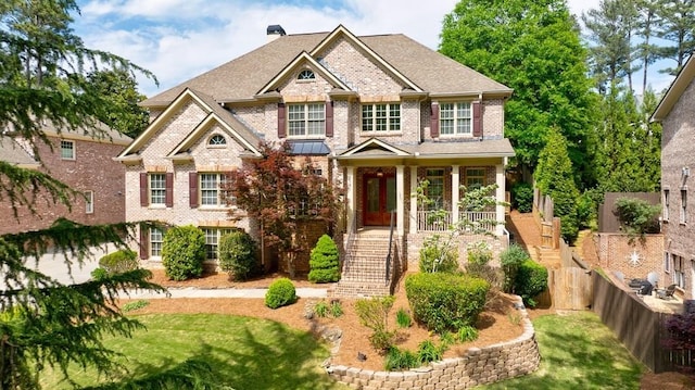 craftsman house with stairway, a front lawn, fence, a porch, and brick siding
