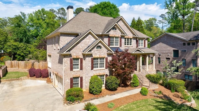 craftsman house featuring a chimney, concrete driveway, fence, brick siding, and an attached garage