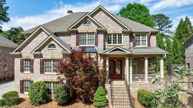view of front of property with brick siding, a porch, and a shingled roof