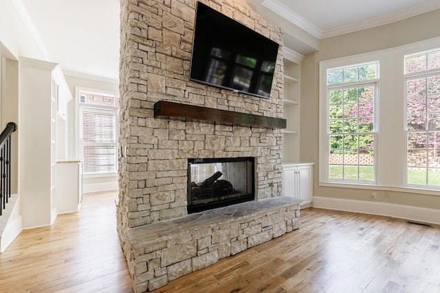 unfurnished living room with a fireplace, wood finished floors, a wealth of natural light, and ornamental molding